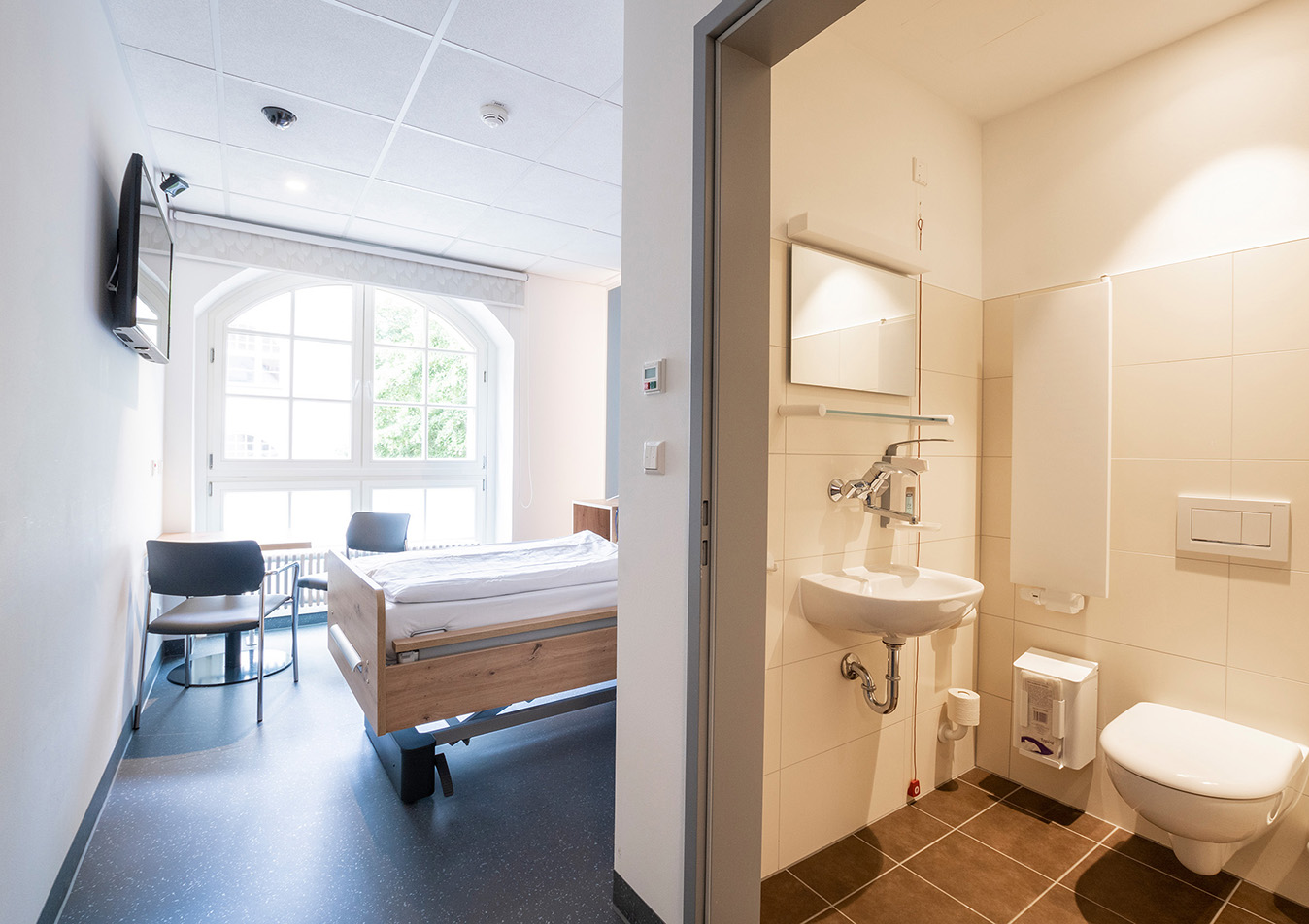 Patientenzimmer mit Bad und großen Fenstern